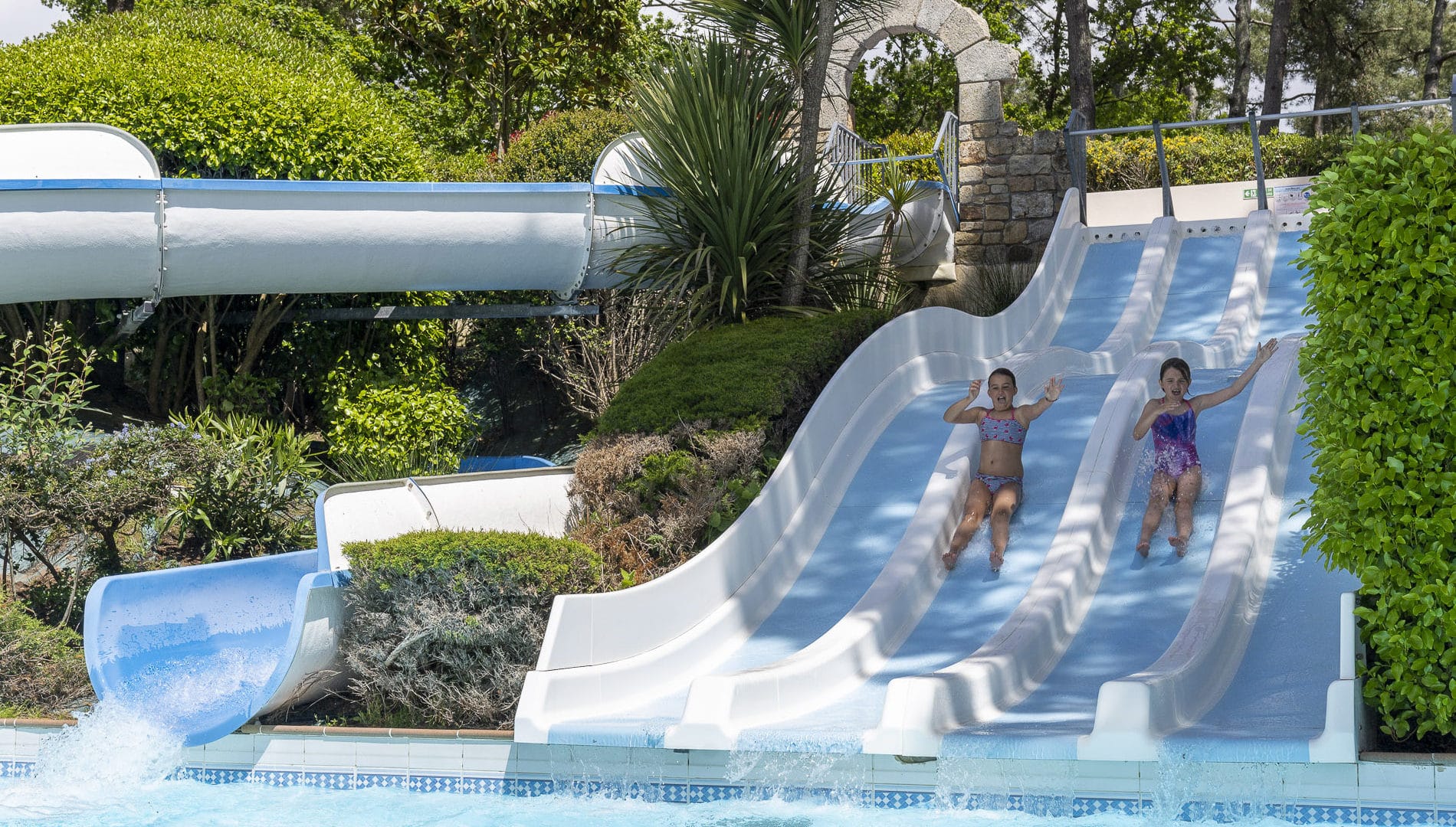 Enfants glissant sur toboggans aquatiques en plein air.