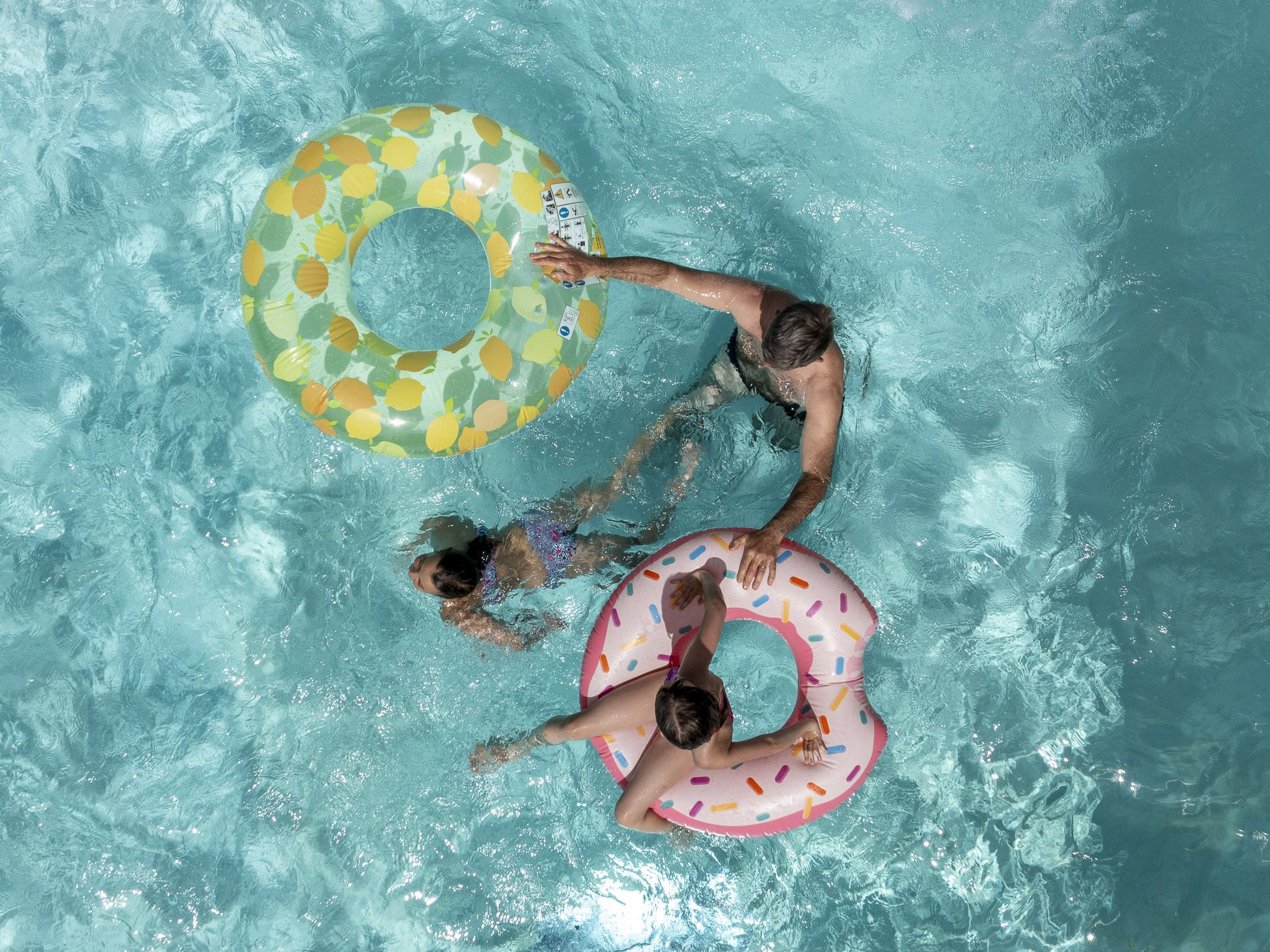 Personnes nageant avec des bouées dans la piscine.