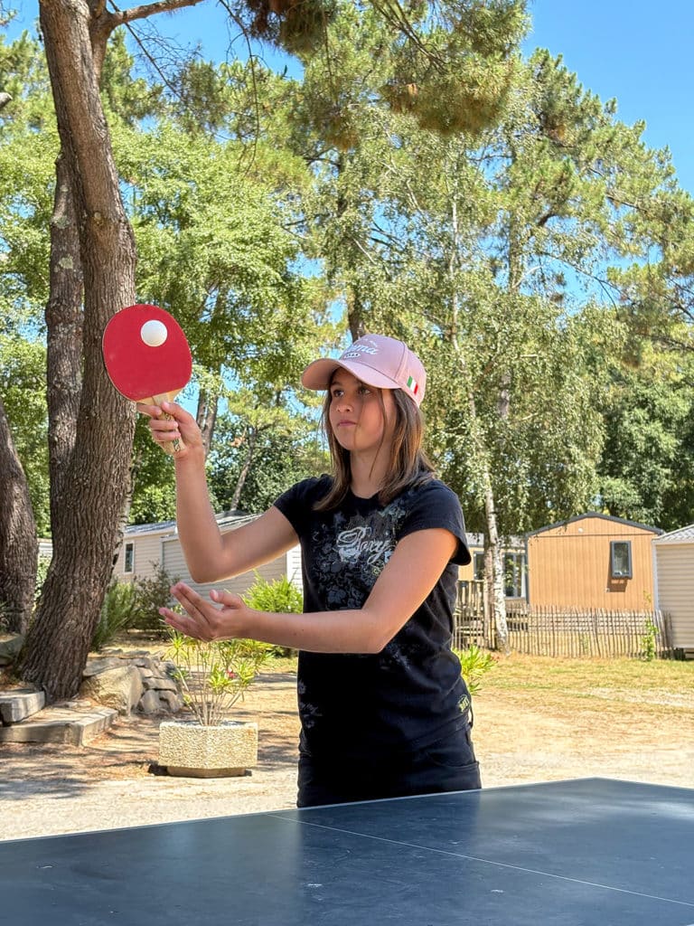 Jeune fille qui joue au tennis de table au camping en Bretagne